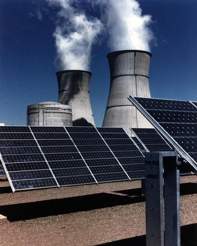 Paneles solares frente a una estación generadora termoeléctrica